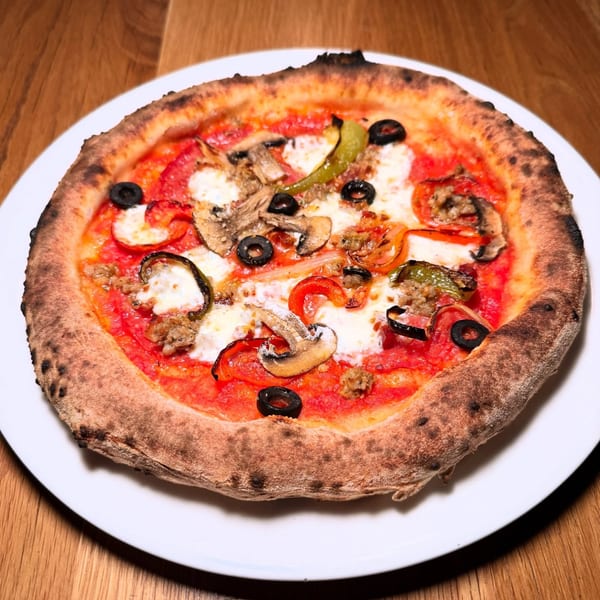 MOROSO Italian Ristorante's pizza with mushrooms, olives, peppers, and sausage on a white plate.