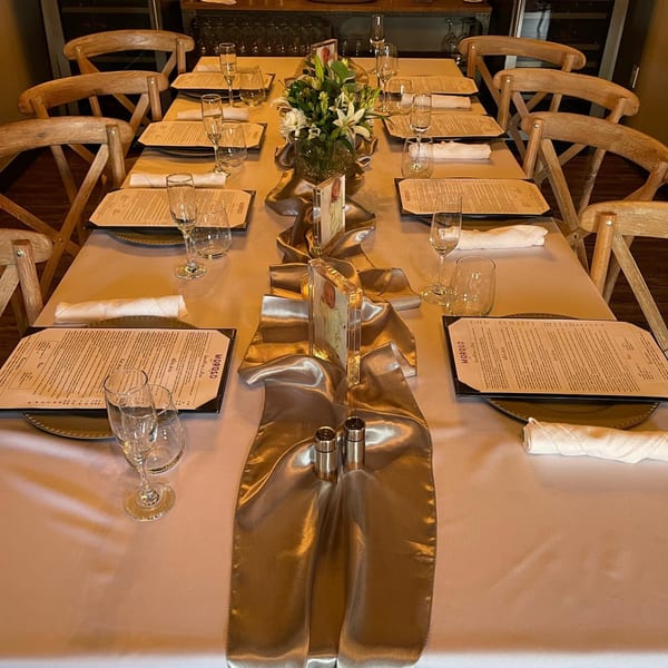 Long dining table set with menus, glasses, and a floral centerpiece at MOROSO Italian Ristorante.