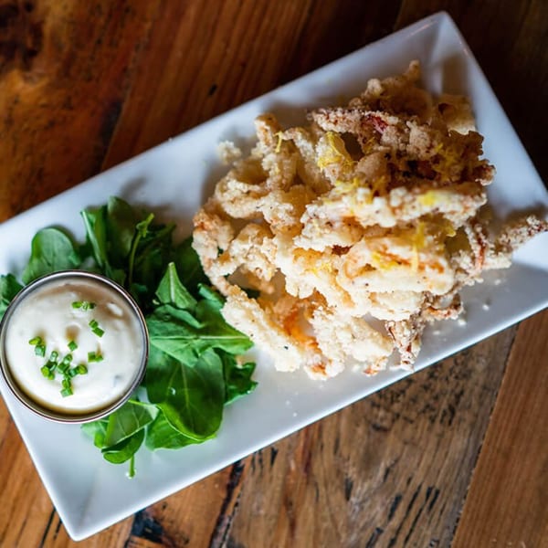 Crispy fried calamari with lemon zest, fresh arugula, and a side of creamy dipping sauce.