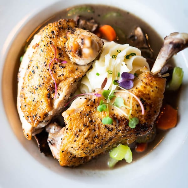 MOROSO Italian Ristorante's roasted chicken with mashed potatoes, vegetables, and gravy in a white bowl.